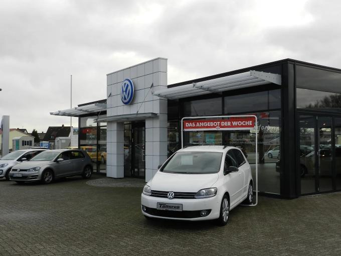 Nahaufnahme von Händen, die einen eleganten Koffer aus dem Kofferraum eines Autos auspacken und dabei Luxusmode präsentieren.