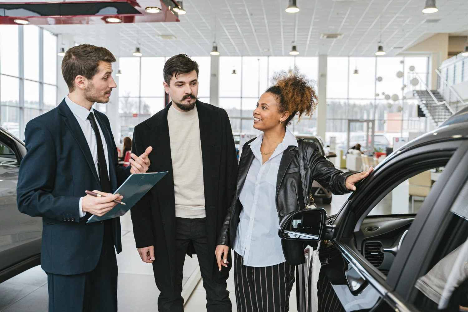 Ein glückliches Paar bespricht den Autokauf mit einem Händler im Ausstellungsraum. Professionelle Interaktion und Beratung.